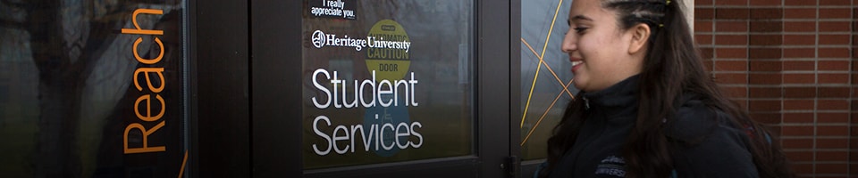 Student entering Student services building at Heritage University
