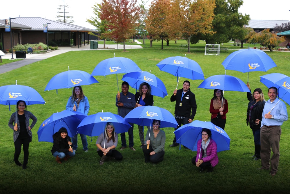 Heritage University group of teachers and students posing outside with blue umbrellas