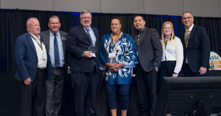 Heritage University administrators holding award and standing on stage with WASA representatives