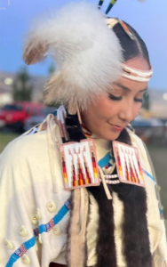 A young woman wearing Native American designed clothing looking downward