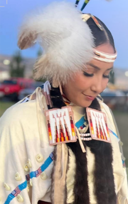 A young woman wearing Native American designed clothing looking downward