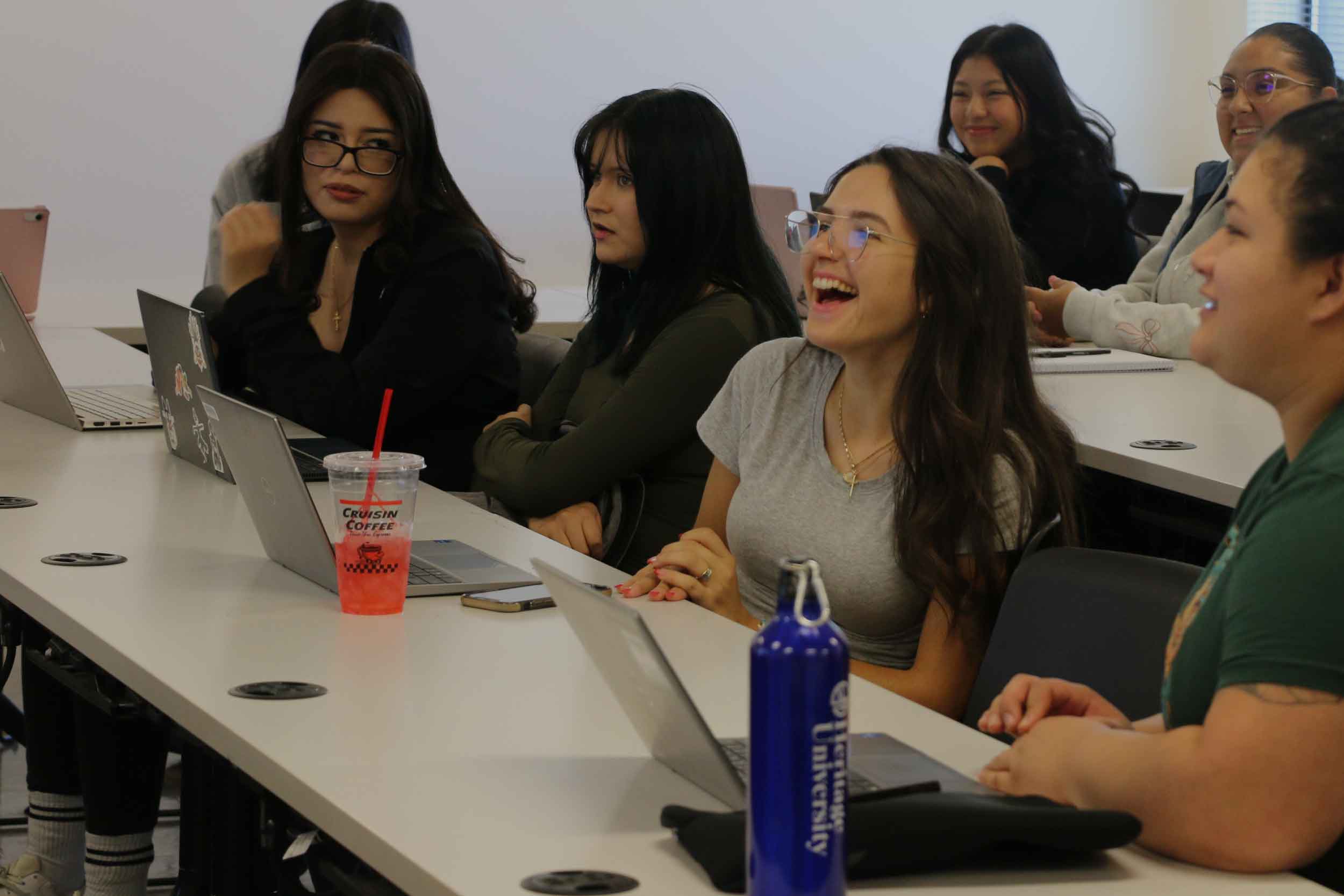 A group of women sitting at tables with laptops