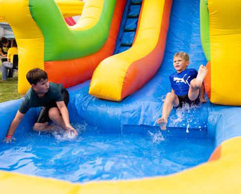HeritageRiseUp-EW-01 Two boys playing in a water slide