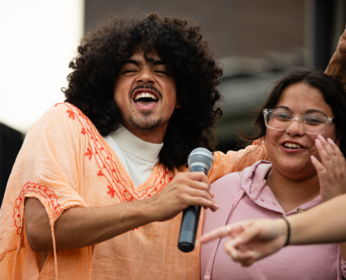HeritageRiseUp-EW-23 A person with curly hair holding a microphone and smiling