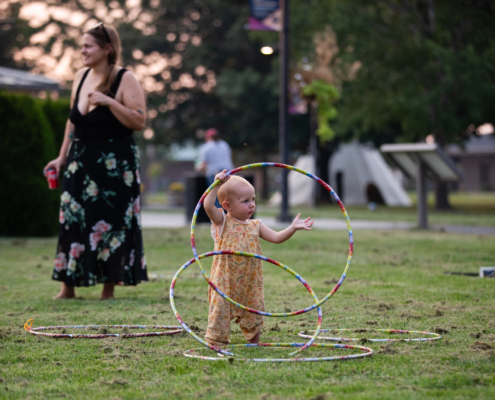 HeritageRiseUp-EW-32 A baby standing in a field with hula hoops