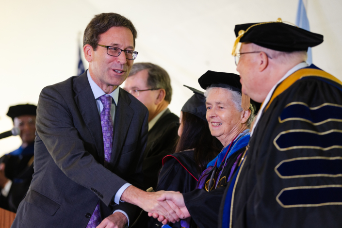 Presidential Inauguration: Installation A person shaking hands with a person in a graduation gown