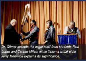 As part of Dr. Chris Gilmer's installation as President of Heritage University, Gilmer met with Heritage University Native American students who presented him with an eagle staff while a Yakama Nation tribal leader explains the staff's significance