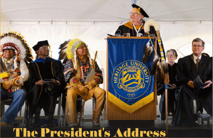 Wings_Fall2025_PresidentialInauguration_3 People in Native American regalia on a stage with people in higher education regalia paying attention to the university president's address