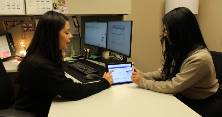 A person showing something on a tablet to another person