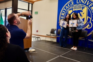 A person taking a picture of a group of women who are holding diploma frames