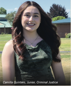 Photograph of a young woman smiling outdoors on a sunny day, wearing a dark green sleeveless dress with long, wavy brown hair. Background includes a grassy area, brick buildings, and trees, with text identifying her as Camilla Quintero, Junior, Criminal Justice.